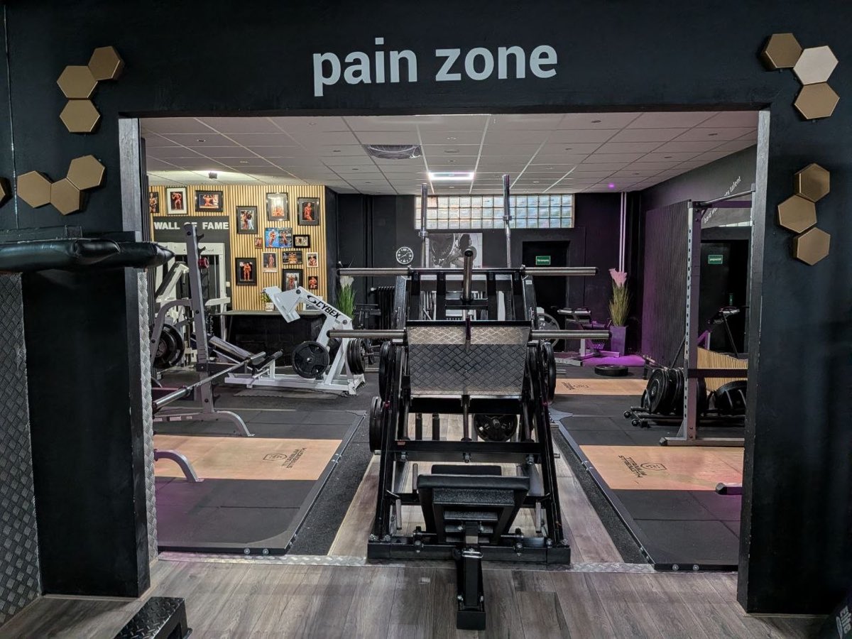 Blick durch den Durchgang zur Pain Zone mit Beinpresse und Squat-Racks